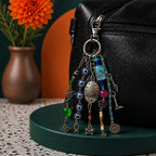 Ariel La Boutique beaded bag charm with evil eye motifs, silver charms, and glass beads attached to a black leather bag.