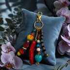 Ariel La Boutique bohemian beaded keychain with red horn, turquoise heart, and crystals on a blue velvet pillow.