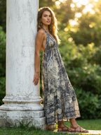 Ariel La Boutique bohemian maxi dress with halter neck and earthy print, worn by a woman leaning against a stone pillar