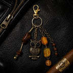 Ariel La Boutique antique bronze owl keychain with amber beads and gold-tone lobster clasp on black leather.