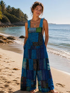 Ariel La Boutique patchwork wide-leg jumpsuit in blue and green tones with textured straps on a sunny beach.