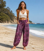 Ariel La Boutique purple bohemian harem pants with drawstring waist and pockets worn by a woman on a sunny beach.