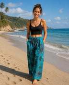 Ariel La Boutique teal patchwork wide-leg lounge pants with black floral print, worn by a woman on a sunny beach.